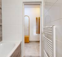 A bathroom in a 3-room apartment with a bathtub and a floor with a wooden decor.