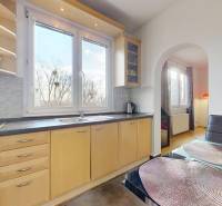A kitchen in a 3-room apartment with a large window, light furniture, and a floor with a wooden decor.