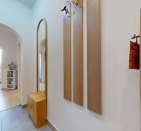 A hallway with tiles and a coat rack leads to a room in a three-room apartment.