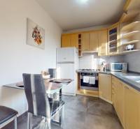 A kitchen in a 3-room apartment with wooden cabinets, a dining table, and appliances.