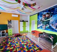 A colorful children's playroom with a poster on the wall, a wooden decor floor, and festive decorations.