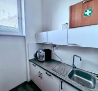 A kitchenette in the office with cabinets, a sink, and a coffee maker.