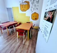 Children's corner with colorful tables, chairs, and a wooden-patterned floor in the office.