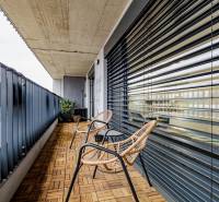 A balcony with a wooden decor floor, rattan chairs, and metal railing.