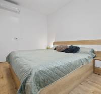 A bedroom in a 3-room apartment with light furniture and a wooden decor floor.