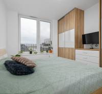 A bedroom with a large window, a bed, and a wardrobe in a 3-room apartment.