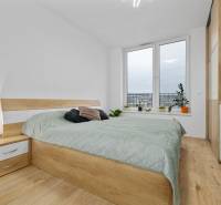 A bedroom in a three-room apartment with a bed, wardrobe, and wooden decor flooring.