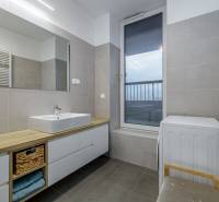 A bathroom in a 3-room apartment with sinks, storage space, a washing machine, and a large window.