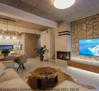 Living room in a family house with a fireplace, TV on a stone wall, and floor with wooden decor.