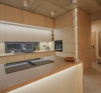 A kitchen in a family house with built-in appliances, countertops, and flooring with a wood design.