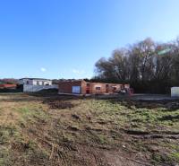 The construction site of a family house in Nitra on Drieňová Street, surrounded by nature and neighboring buildings.