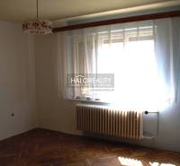 A room with curtains and a radiator, a floor with a wooden decor in a family house.