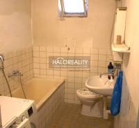 Bathroom with an older bathtub, sink, and washing machine in a family house.