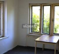 Bright room in a family house with windows, an older table, and a dark floor.