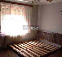 Bedroom in a family house with a bed and a radiator, wooden decor flooring, curtains.