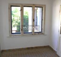 A room in a family house with a tiled floor and windows facing greenery.