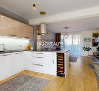 Kitchen with dining area, modern equipment, wooden floor, light red cabinets, family house.