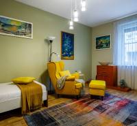 A room in a family house with a colorful carpet and a yellow armchair, wooden decor flooring.