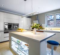 A kitchen in a family house with a central island, white cabinets, and appliances.