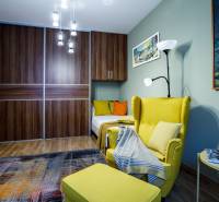 A room with a comfortable armchair, wardrobe, chandelier, and a floor with a wooden decor in a family house.