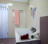 A bathroom in a family house with a bathtub, a pink towel, and decorative candles.