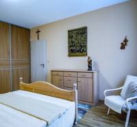 Bedroom in a family house with wooden furniture, bed, wardrobe, armchair, floor with wooden decor.