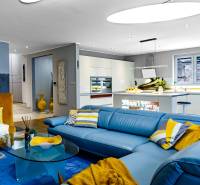 Living room in a family house with a blue sofa and a kitchen, floor with wood decor.