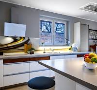 A kitchen in a family house with a stylish countertop, white cabinets, and window decorations.