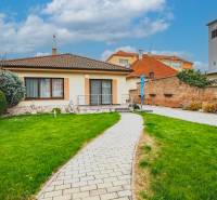 A family house on Školská Street in Senec with a garden, a walkway, and a tower in the background.
