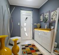 Entrance hall of a family house, white furniture, yellow vases, and a colorful carpet.