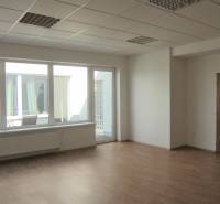 A spacious office with large windows and a wooden decor floor.