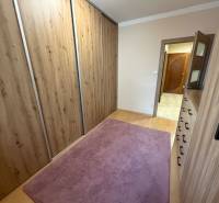 A hallway in a 4-room apartment with carpet and flooring with a wood design.