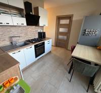 A kitchen in a 4-room apartment with a wooden decor floor and built-in appliances.