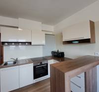 A kitchen in a 4-room apartment with white cabinets and a wooden decor floor.