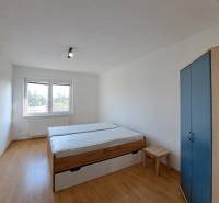 A bedroom in a 4-room apartment with a bed, wardrobe, and wooden decor flooring.