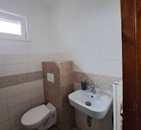 A toilet in a 4-room apartment with white and patterned tiles.