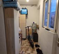 A narrow hallway in a family house with shelves, a window, an electric scooter, and shoes.