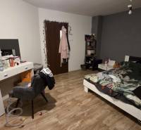 Bedroom with a bed, desk, and wooden floor decor in a family house.