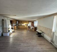 Interior of a family house with a kitchenette, a masonry stove, and a wooden-patterned floor.