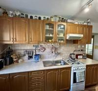 Kitchen in a 2-room apartment with wood decor on the floor and wooden cabinets.