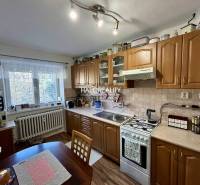 A kitchen in a 2-room apartment with a wooden floor decor and classic cabinets.