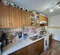 A kitchen with cabinets in a 2-room apartment with a wood-patterned floor.