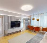 Living room in a 3-room apartment with a TV on the wall, a sofa, and a dining table.