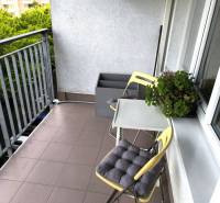 A balcony of a 2-room apartment in Bratislava with chairs and greenery, suitable for relaxation.