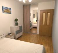 Bedroom in a 2-room apartment with a wooden decor floor, wardrobes with a mirror and a painting.