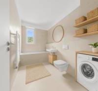 Bathroom with a bathtub, sink, mirror, and washing machine in a 2-room apartment.