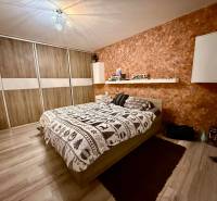 Bedroom in a two-room apartment with a bed, storage space, and a wooden decor floor.
