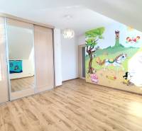 Children's room with wood-patterned flooring, sliding wardrobe, painted wall with a nature motif.