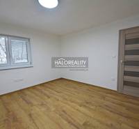 An empty room in a family house with a wood-patterned floor and a window.