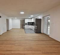 Living room in a family house with a kitchen, wooden decor flooring, white walls.